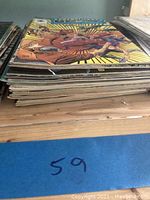 Side view showing a stack of around 11 vintage comic books with colorful covers and some wear on edges.