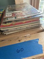 Stack of 11 comic books showing different colorful covers and signs of slight wear and scratches. Protective plastic sleeves can be seen on some comics.