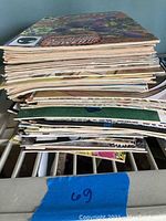 Stack of 16 assorted comic books viewed from the side showing some bending and wear on edges.