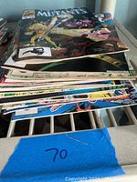 Stack of 17 comic books seen from side angle showing multiple colorful covers and spines