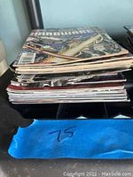 Stack of comic books showing thickness and condition, some signs of wear and use on spines and edges