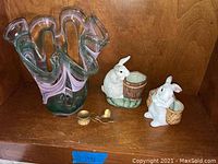 Image showing lot of two porcelain rabbit figurines and one modern glass dish on wooden shelf.