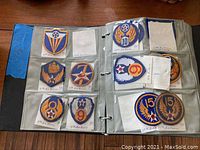 Two open binder pages showing nine vintage Air Force patches in plastic sleeves with handwritten labels identifying the units.