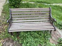 Front view of the wooden outdoor bench showing horizontal slats and metal frame.