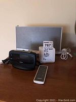 Full view of Bose SoundDock Portable system, Ingraham alarm clock, and Bose remote control on wooden surface.