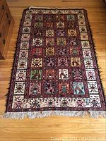 Full view of the handwoven area rug displaying the complete folkloric geometric pattern and fringed ends on hardwood floor