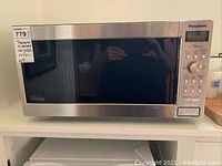 Front view of microwave showing control panel, brand, and model sticker.