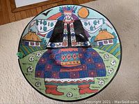 Top down view showing entire decorated bowl with folk art scene, including houses, crowned woman, flowers, sun, and bird.