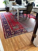 Rug under desk with clear protector mat, showing overall size and condition.