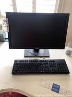 Full view of Dell monitor and keyboard on white desk, showing front monitor screen and keyboard layout.