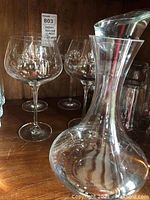 Front view of the decanter with stopper and four balloon wine glasses on wooden surface