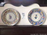 Two Mediterranean-style decorative plates with floral motifs, placed side by side for scale and comparison.