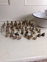 Wide view showing over 50 Wade ceramic figurines arranged on table with white enamel bowl present.