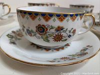 Close-up of the teacup and saucer showing the colorful Vignaud floral pattern with gold trim.