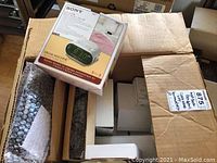 Box containing multiple electronics, including boxed Sony Dream Machine clock radio and other items packed inside with bubble wrap.