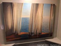 Full view of the photographic canvas art hung on a wall showing sheer curtains opening toward sea.
