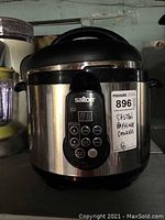 Front view of Salton electric pressure cooker showing stainless steel body, black lid, and front digital control panel with MaxSold tag.