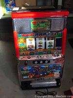 Front view of vintage fruit machine showing colorful slot reels and artwork, with chrome and red side accents