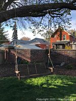 Front view of wooden porch swing hanging from tree