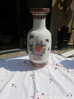 Full view of tall porcelain vase showing peacock, flowers and butterfly designs with ruler for scale.