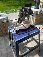 Front angle of Jobmate electric table saw on the blue Mastercraft metal stand placed outdoors on stone patio.