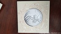 Photo of coin face showing Bugs Bunny image and 2015 date with background art on display card.