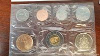 Front side of seven Canadian coins including penny, nickel, dime, quarter, 50-cent, loonie and toonie in clear plastic holders