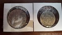 Two Canadian coins from 1969, one dollar and fifty cent coins, stored in cardboard holders with plastic windows.