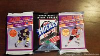Three unopened NHL hockey card packs: one 1990-1991 Upper Deck High Series in the middle and two 1991-1992 Score on either side.