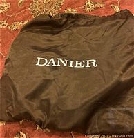 Brown fabric dust bag with 'DANIER' printed in white on the front