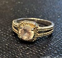 Close-up photo of the ring's top view showing the round light pink stone and beaded bezel setting