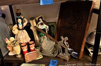 Vintage ceramic figurines, carved wooden panel, glassware and metal decorative items grouped on shelf