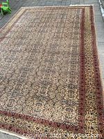 Full view of rug laid flat on stone pavers showing overall pattern, borders, and fringe