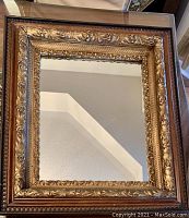 Full frontal photo of the antique mirror showing its ornate gilded frame and reflective glass surface.