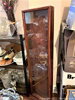 Front view of antique shadow box showing wood frame and glass front door with visible shelves inside.