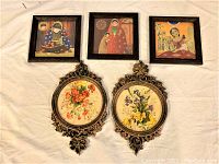 Five wall decorations laid out: three square framed traditional-style prints and two ornate oval floral paintings.