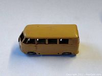 Side view of a yellow toy Volkswagen Micro Bus showing windows and wheels with visible age wear and paint scratches.