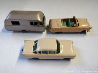 Side view of three vintage Lesney Matchbox die-cast vehicles including Ford Zodiac convertible, hardtop sedan, and caravan trailer showing scale and colors.