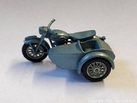 Side view showing the motorcycle with attached sidecar, metallic blue-gray paint, with some wear marks and detailing on wheels and body.