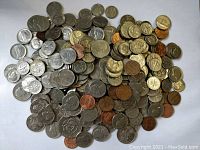 Top view showing a large assortment of USA pennies, nickels, dimes, and quarters mixed together on a white background.
