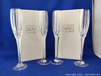 Four Mikasa Northern Lights flute glasses shown with their original white boxes labeled Mikasa against a blue background.