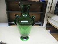 Front view of the vintage green art glass jug with flared rim and two handles.