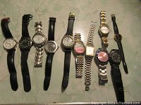 Overview of eleven men’s watches laid flat; various straps and bracelets