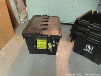 Black plastic storage bin with hinged lid and yellow return to Thrifty Foods label on front