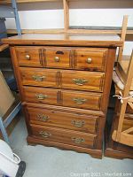 Full front view of pine highboy dresser showing five drawers with two different styles of hardware.