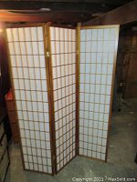 Full view of the three-panel wooden folding screen standing upright showing paper inserts and wood grid frame.