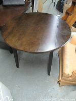 Photo of the round wooden bistro table showing the top surface and straight legs.