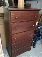 Front view of veneered high boy dresser showing five drawers with wooden knobs and dark wood finish.