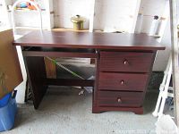 Front view of the solid wood desk showing the table top, pedestal with three drawers, and crossbar support underneath.