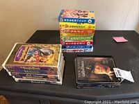 Photo of three stacks of DVDs and VHS tapes showing various titles on a black surface.